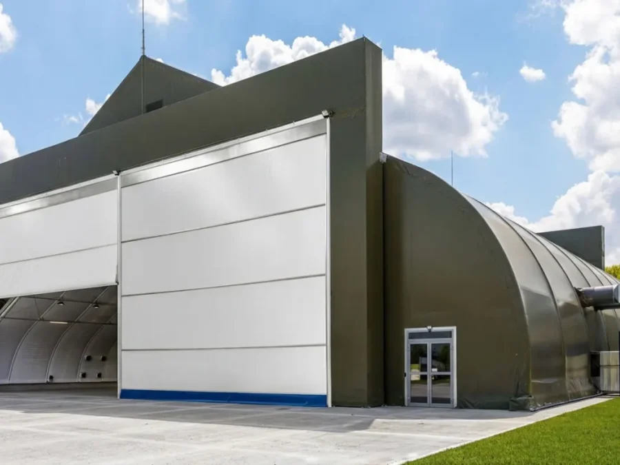 Hangar materiałowy w kolorze oliwkowym z jednym skrzydłem bramy otwartym